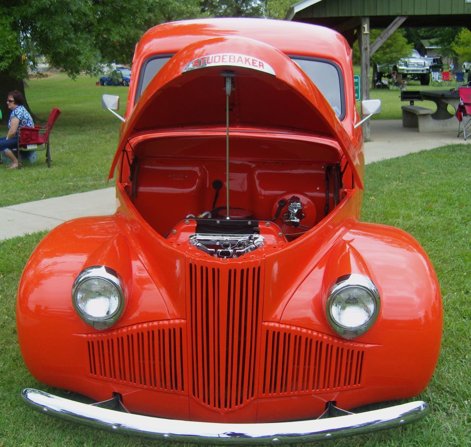 Orange Studebaker truck with hood open, chrome bumper, vertical grille
