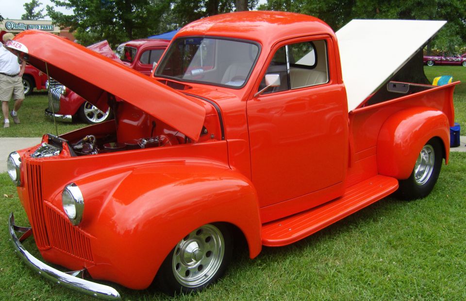 Orange pickup truck with hood open, white tonneau cover raised