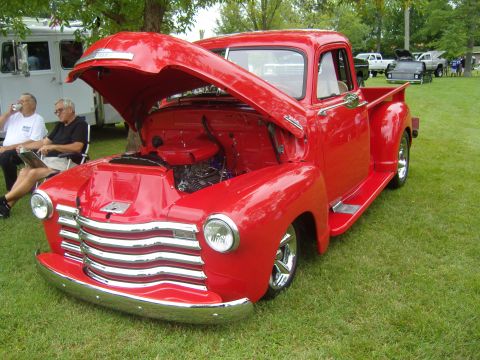 2007 Ford Mustang - Classic red Chevrolet pickup truck displayed with its hood open at an outdoor event.