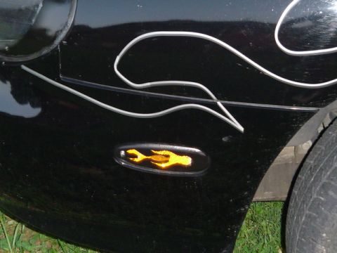 1999 Ford Taurus - A close-up view of a black car's fender shows custom flame graphics and a unique turn signal.