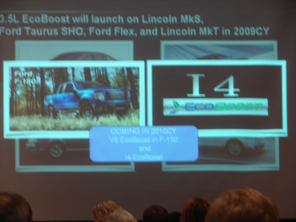 Blue Ford F-150 truck in woods, with screen showing I4 EcoBoost logo and text about upcoming engines