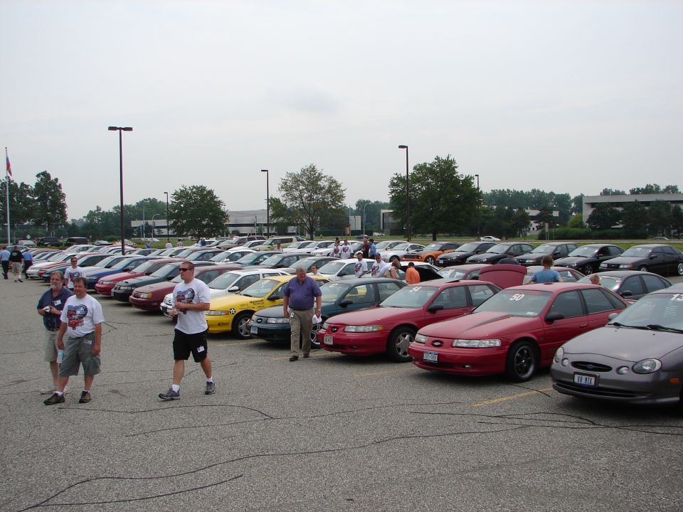 Several 1992 Ford Taurus cars parked in a lot with people walking around