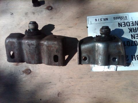 1978 Ford Bronco - Two old metal brackets, possibly for a vehicle, sit on a wooden surface next to a paper with Swedish writing.