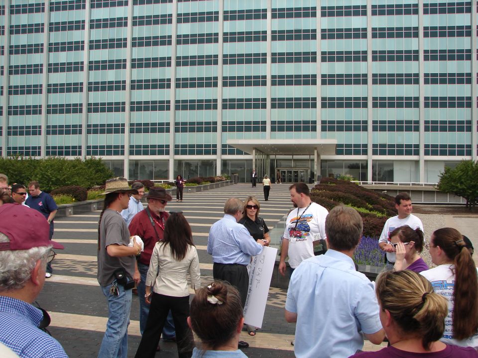 Group of people gathered outside a large office building with a patterned walkway