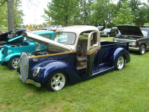 2007 Ford Mustang - A customized 1937 Ford pickup truck is displayed at an outdoor car show with other vehicles.