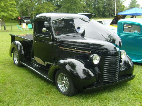 2007 Ford Mustang - A black pickup truck is displayed with its hood open at an outdoor event.