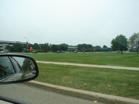1992 Ford Taurus - A reflection in the side view mirror shows several cars driving on a road, with a large grassy area and buildings visible beyond.