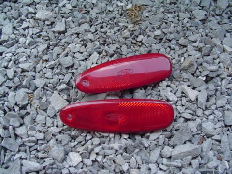 1999 Ford Taurus - Two red Ford side marker lights are shown resting on a bed of gravel.