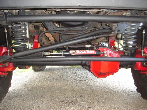 1989 Ford Bronco - The photo shows the front axle and suspension components of an off-road vehicle, including a steering stabilizer.
