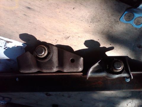 1978 Ford Bronco - Two metal brackets with bolts are shown on a wooden surface.