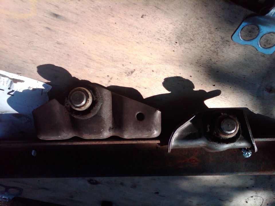 Two metal brackets with bolts on a wooden surface