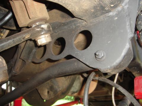 1989 Ford Bronco - Underside view of a vehicle's suspension component, showing a metal bracket with holes.