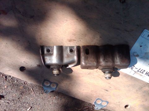 1978 Ford Bronco - Two metal brackets with rubber isolators are shown on a wooden surface.
