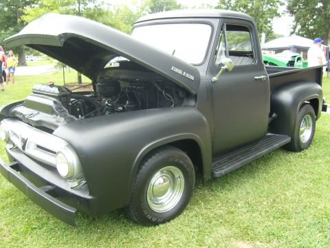 2007 Ford Mustang - A matte black 1953 Ford F-100 truck is displayed with its hood open, revealing the engine bay.
