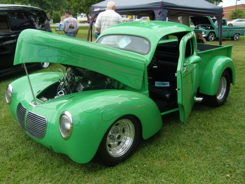2007 Ford Mustang - Custom green pickup truck with flame graphics and exposed engine at an outdoor car show.