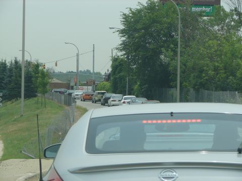 1992 Ford Taurus - A line of cars are stuck in traffic on a road with trees and a billboard in the background.