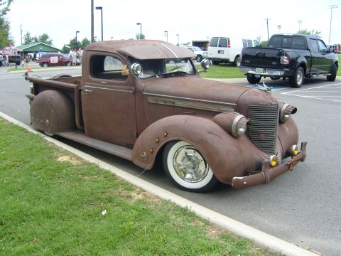 2007 Ford Mustang - A weathered pickup truck with a unique grille and rounded fenders sits parked at an outdoor event.