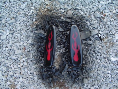 1999 Ford Taurus - Two car parts with flame decals are placed on a bed of gravel and ash.