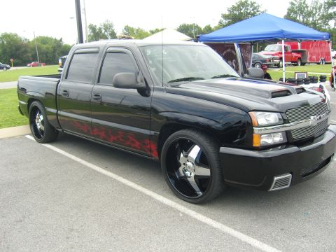 2007 Ford Mustang - Modified black pickup truck with flame decals and custom wheels parked outdoors.