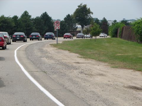 1992 Ford Taurus - Several cars are driving in a line on a paved road with a gravel shoulder.