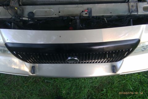 2000 Mercury Grand Marquis - Close-up view of a car's front grille and the opening to the engine compartment.