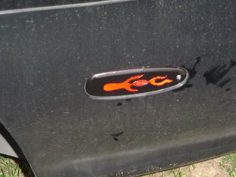 1999 Ford Taurus - Close-up of a black car's side marker light an orange flame graphic.