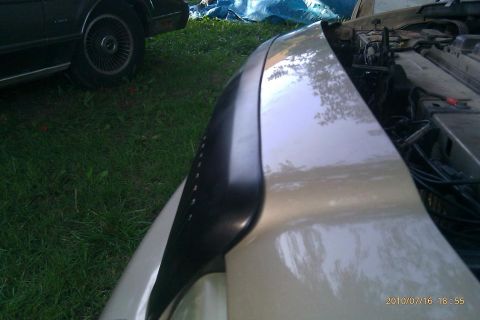 2000 Mercury Grand Marquis - A close-up view of a car's fender and engine bay, with another vehicle partially visible in the background.