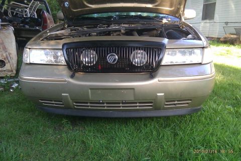 2000 Mercury Grand Marquis - The front of a gold 2000 Mercury Grand Marquis is shown with its hood open, parked on grass.