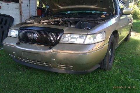 2000 Mercury Grand Marquis - Front view of a 2000 Mercury Grand Marquis, hood up, revealing engine and air intake.
