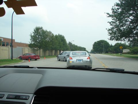 1992 Ford Taurus - A silver coupe is followed by other vehicles on a suburban street.