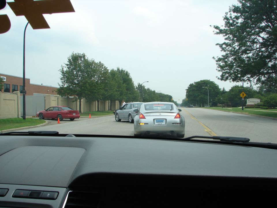 Silver coupe with a license plate visible, seen from behind on a road