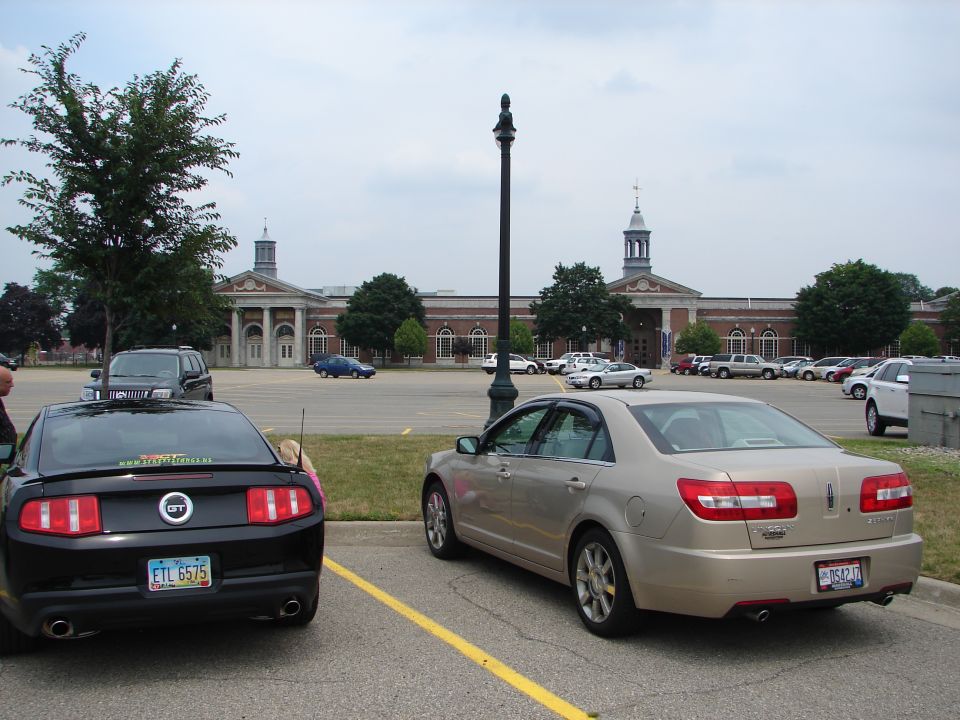 Rear view of a black Ford Mustang and a tan Lincoln MKZ parked in a lot
