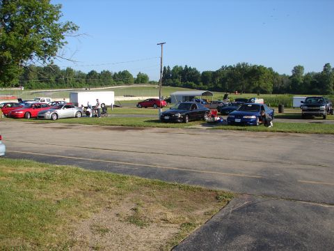 1992 Ford Taurus - A sunny day at the racetrack with several cars and trailers visible.