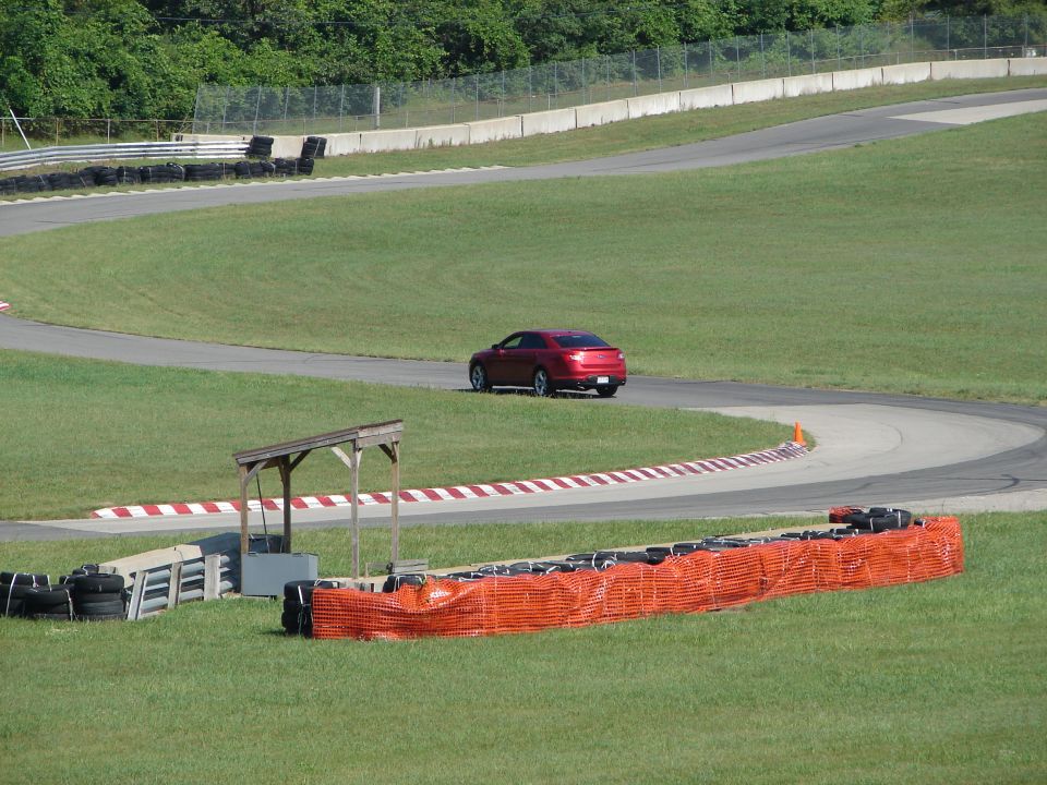 Red sedan on a race track, viewed from the rear
