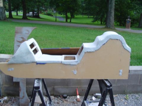 1999 Ford Taurus - Unfinished car interior mock-up in primer stage, resting on sawhorses outdoors.