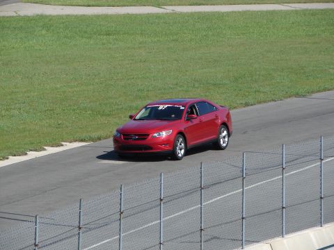 1992 Ford Taurus - A red sedan with racing decals drives on a track, not a 1992 Ford Taurus.