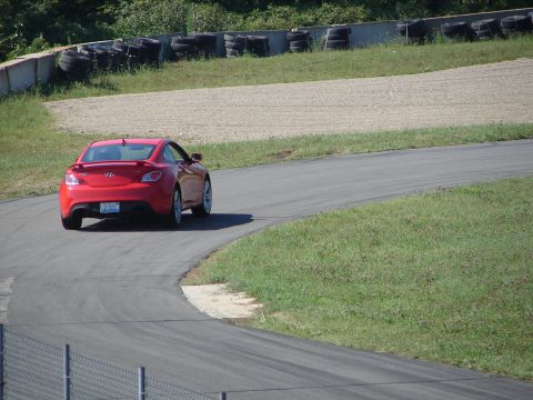 1992 Ford Taurus - A red coupe navigates a turn on a race track, showing its rear profile and a visible license plate.