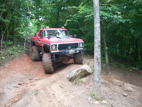 1979 Ford Bronco - A modified red Ford F-150 navigates a challenging off-road course.
