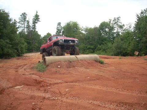 1979 Ford Bronco - This lifted pickup truck is navigating an obstacle course with large concrete pipes.