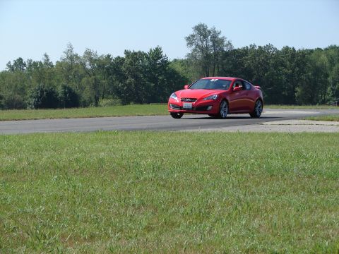 1992 Ford Taurus - Red coupe on race track, trees and grass visible in background.