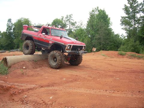 1979 Ford Bronco - This modified SUV is navigating an obstacle course on a dirt track.