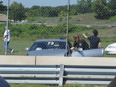 1992 Ford Taurus - A gray 1992 Ford Taurus is visible behind a fence, with people inside and a white car to its right.