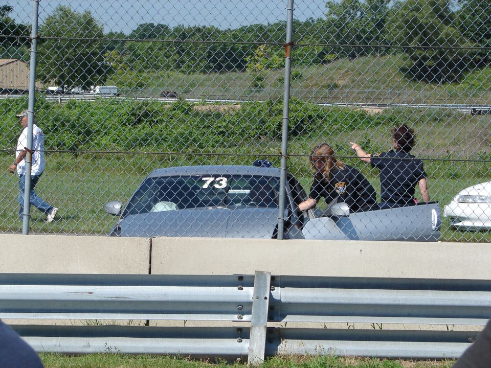 Gray 1992 Ford Taurus with number 73 on the door, seen from the side behind a chain-link fence