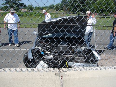 1992 Ford Taurus - Spectators observe a silver car with its hood open, revealing the engine compartment.
