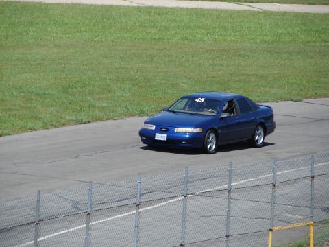 1992 Ford Taurus - A blue sedan is seen on a racetrack, possibly during an event or track day.
