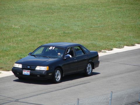 1992 Ford Taurus - A black 1992 Ford Taurus is seen on a racetrack, displaying the number 81 on its windshield.