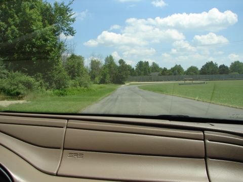 1992 Ford Taurus - Interior view of a car looking out onto a road on a sunny day with clouds.