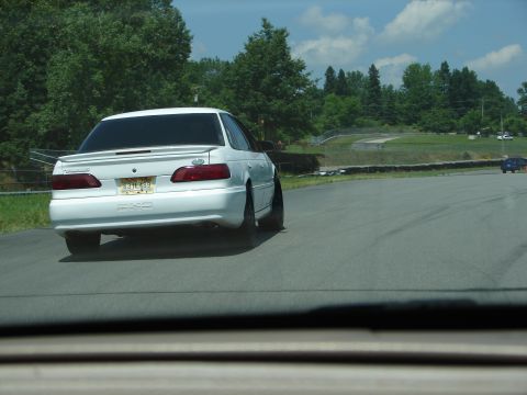 1992 Ford Taurus - A white 1992 Ford Taurus is seen on a race track, with another car in the distance.