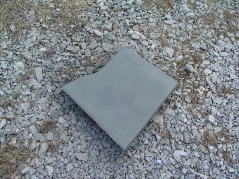1999 Ford Taurus - A gray primer panel rests on a surface of gravel and dry grass.