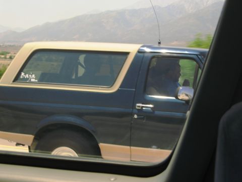 1986 Ford Bronco - A 1986 Ford Bronco is seen from the side, a two-tone paint scheme and a "Baja" decal on the rear window.
